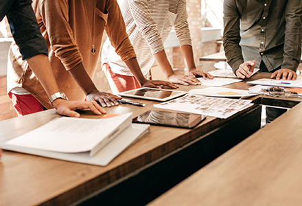 Group of people leaning on a conference room table discussing content