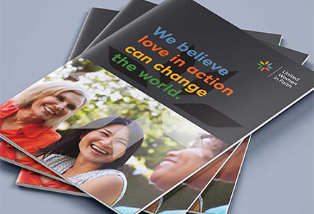 brochure that says "we believe love in action can change the world" on a grey background