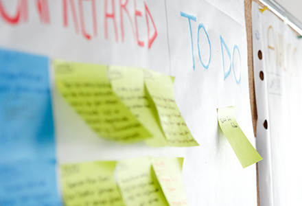 Photo of Post-it notes on a wall with a section of "To Do."