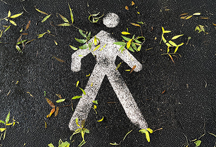 Pedestrian stencil on a pathway with fall leaves