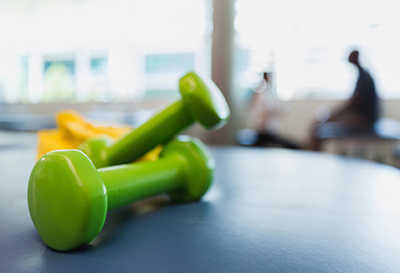 Photo of two green dumbbell weights on a table in a gym.