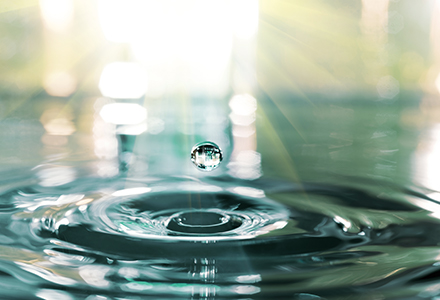 Photo of a water droplet hitting the surface of water and rippling out