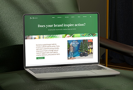 Laptop with 5 by 5 Design home page on the screen