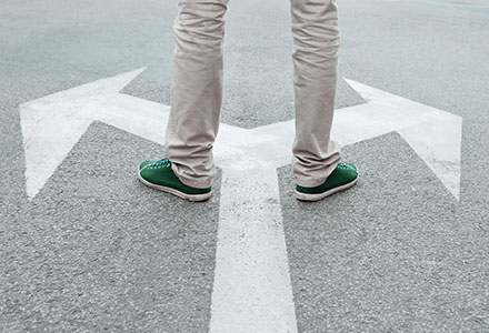 Person's legs with two arrows in opposite directions on pavement