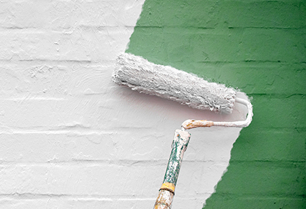 Photo of a paint roller rolling paint onto a brick wall