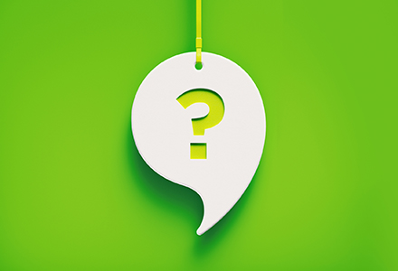 Photo of a white talk bubble with a question mark hanging over a green background