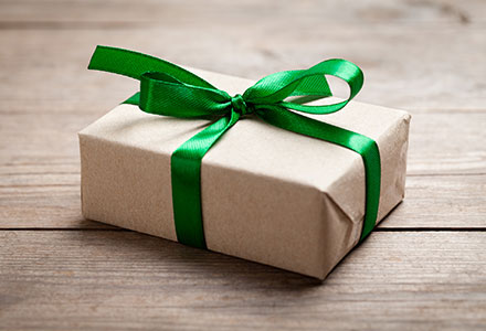 Photo of a brown paper package tied with a green ribbon on a wood surface.