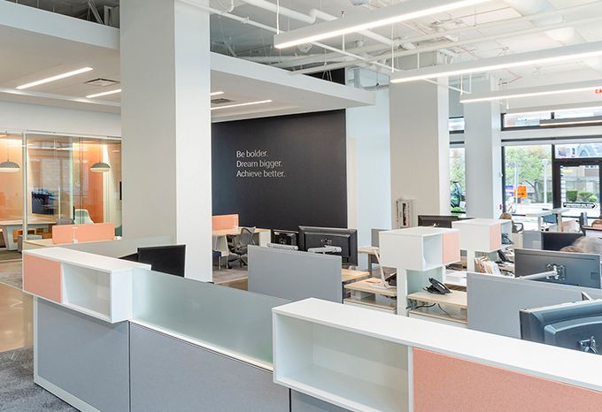 Photo of an office space for APG Office Furnishings with the tagline: Be bolder. Dream bigger. Achieve better. in metal letters on the wall