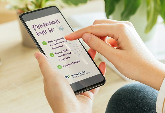 Person holding a phone looking at a social media animation for the Minnesota Board of Cosmetology highlighting the requirements for disinfectants in a salon